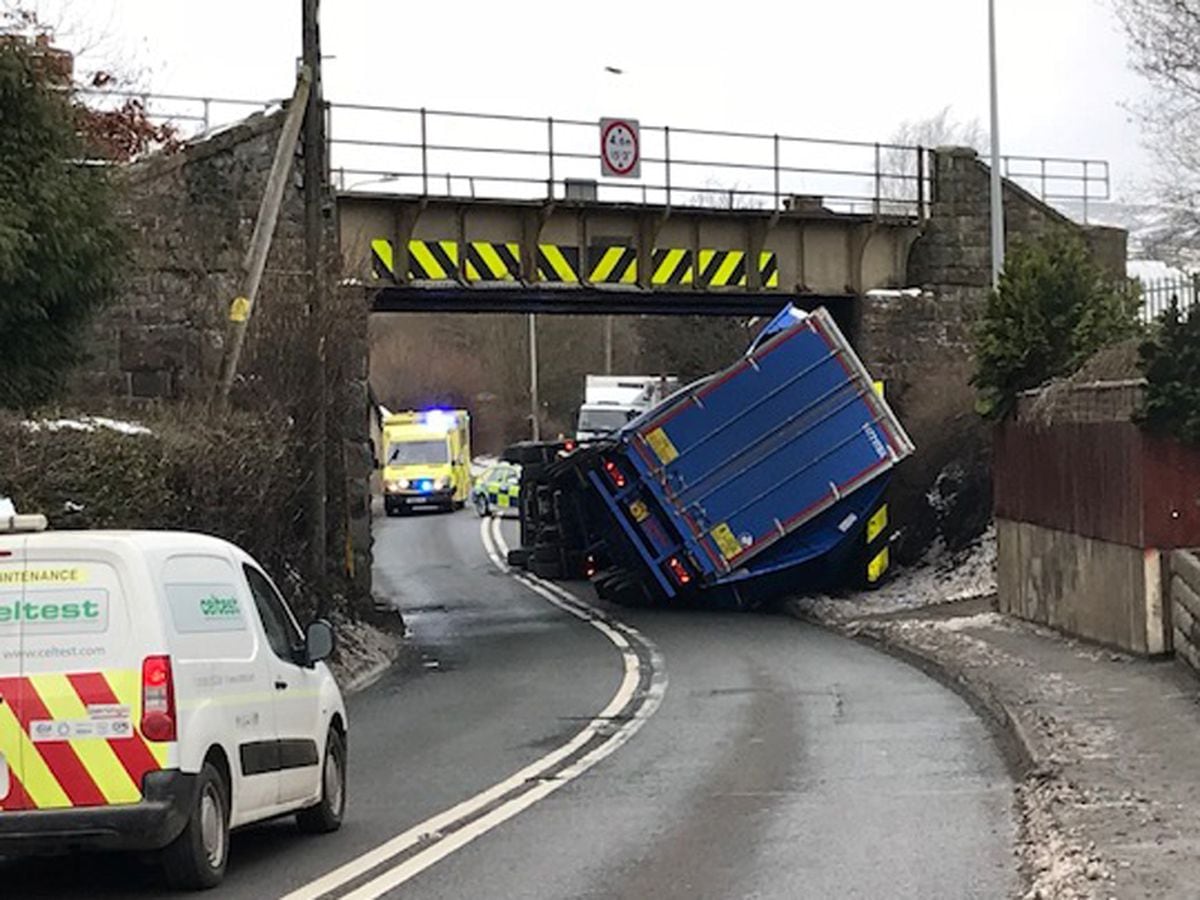 Road blocked and trains delayed after bridge crash lorry overturns