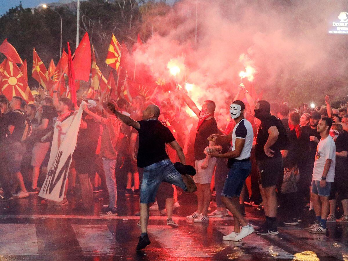 People light flares and throw eggs and stones at the Foreign Office building during a protest in Skopje, North Macedonia, late Tuesday, July 5, 2022