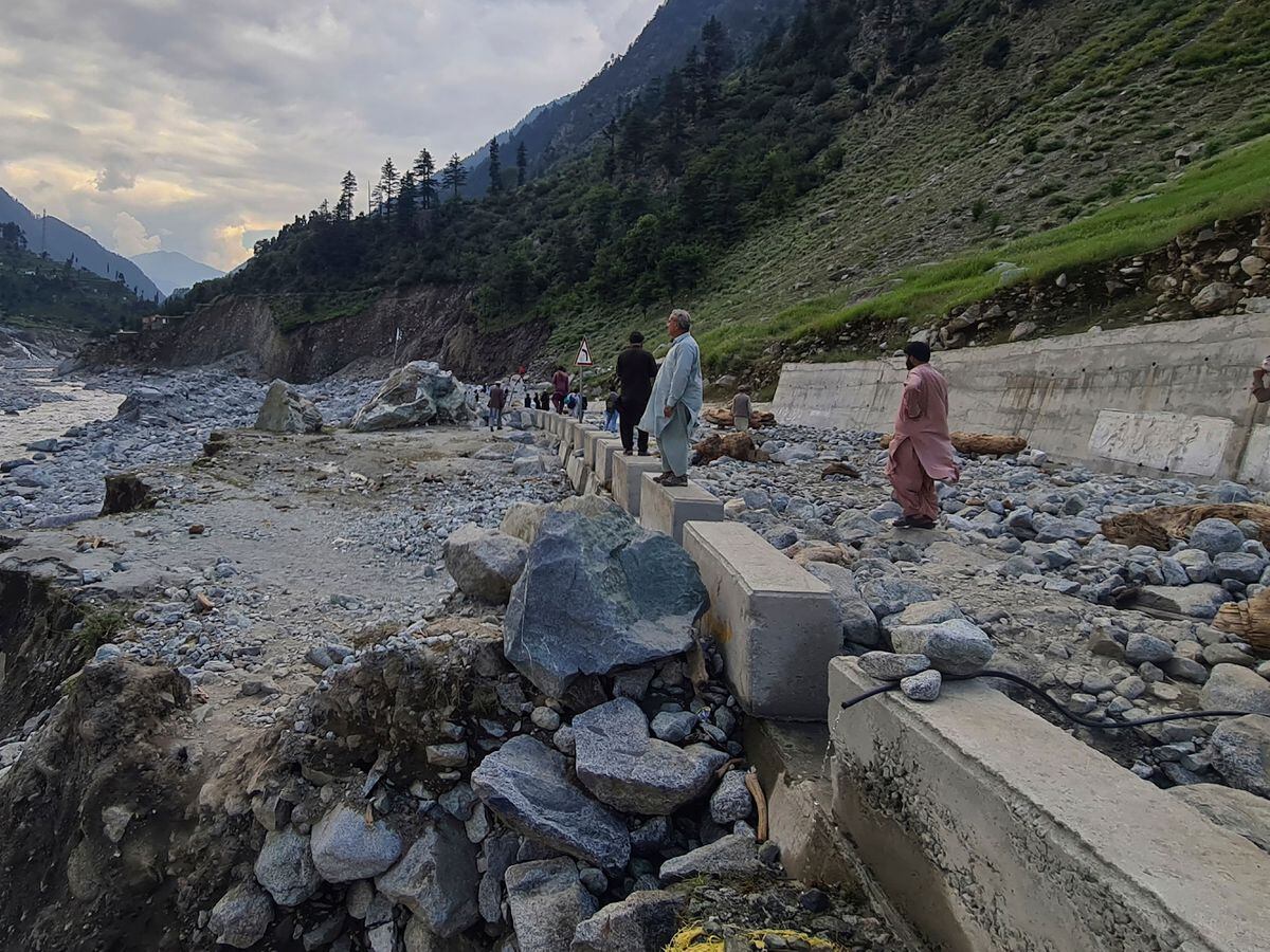 Residents examine a portion of road destroyed by floodwaters in the Kalam Valley in northern Pakistan