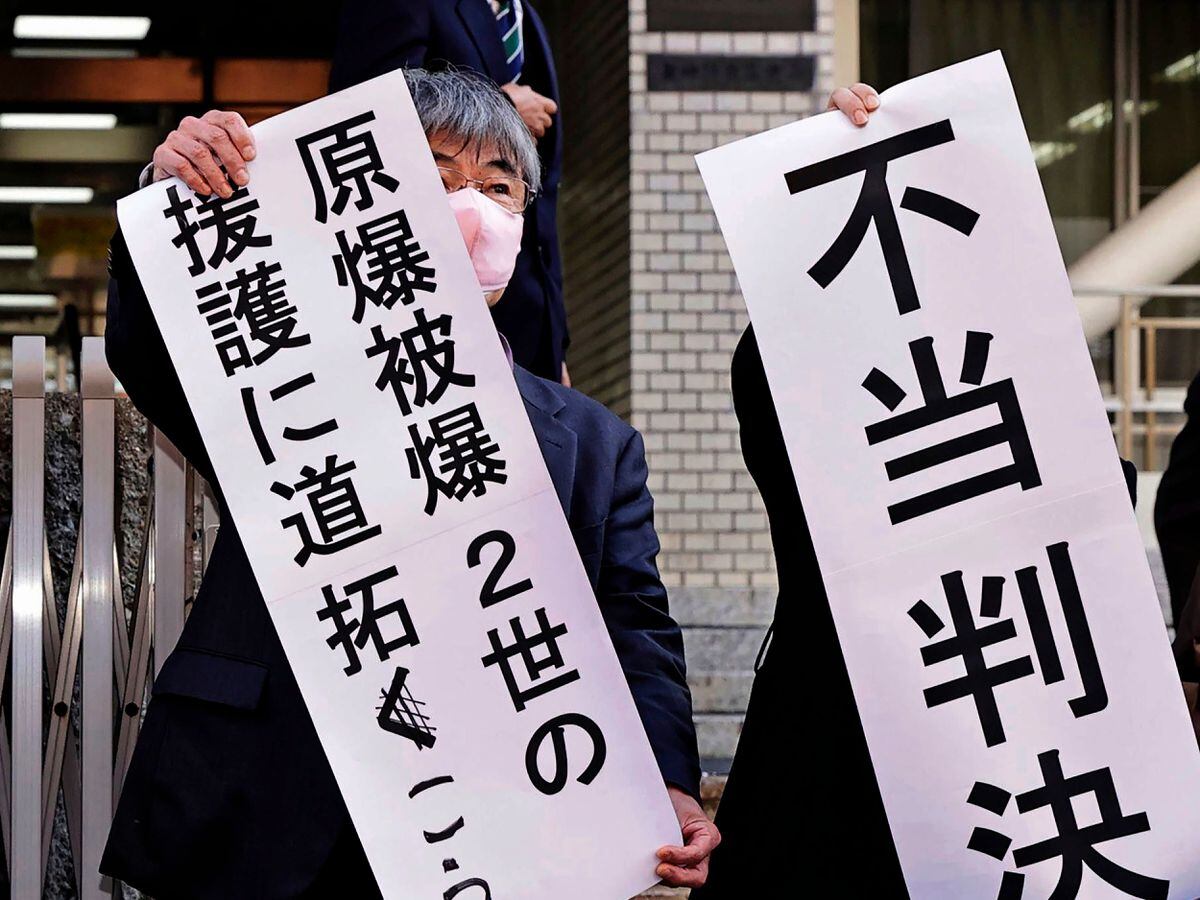 Noboru Sakiyama, left, head of the plaintiffs, holds a banner outside the Nagasaki District Court