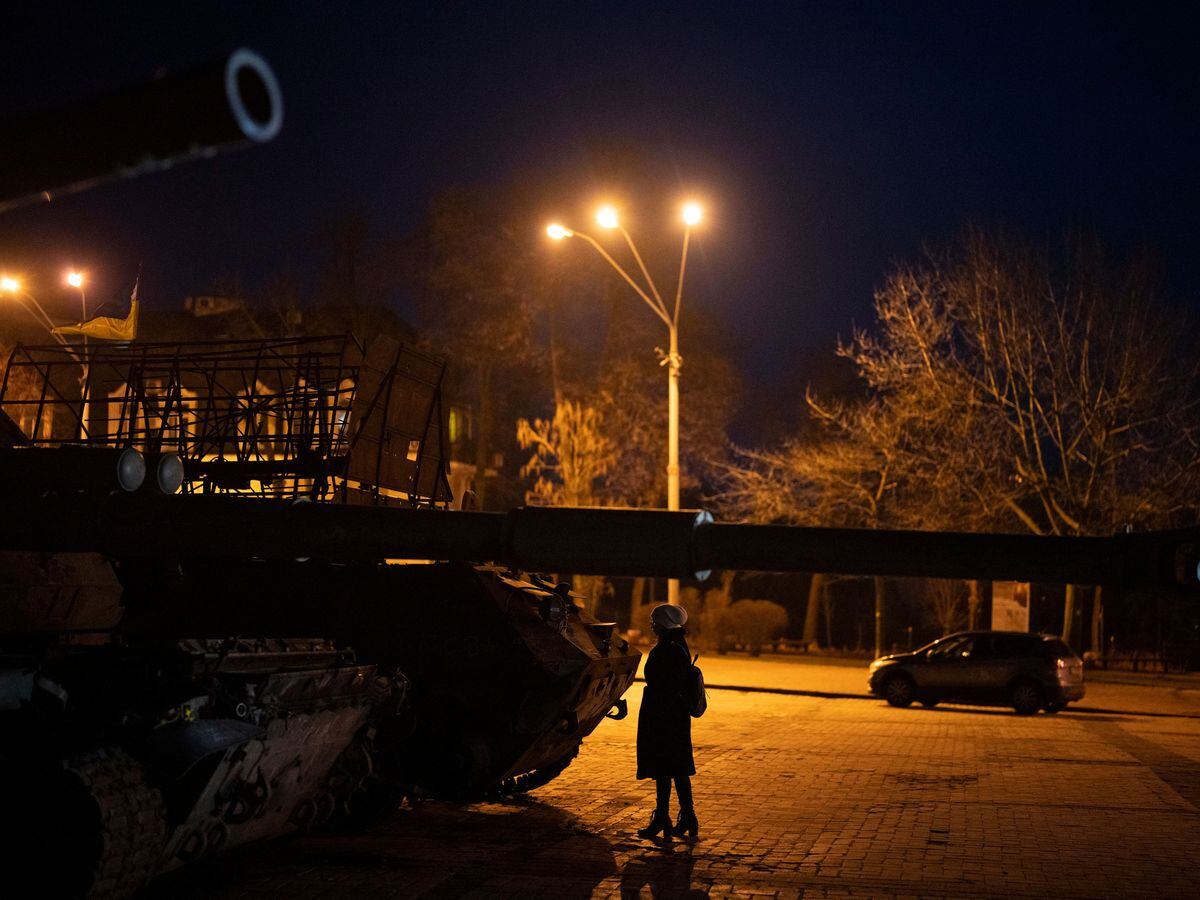 A woman stands in front of a display of destroyed Russian tanks and armored vehicles in Kyiv