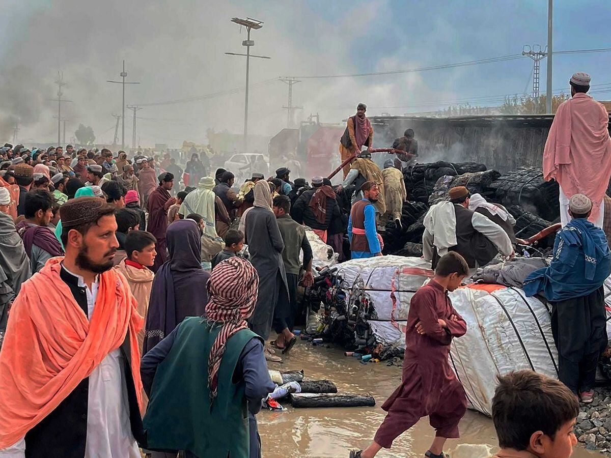 People gather around a truck burned by Afghan shelling in Chaman, southwest Pakistan