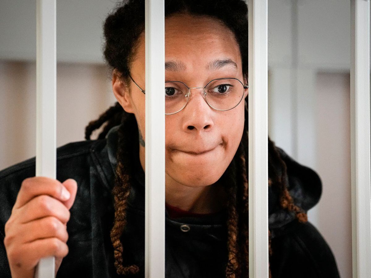 Brittney Griner speaks to her lawyers standing in a cage at a courtroom prior to a hearing in Khimki, just outside Moscow, Russia