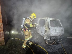 A firefighter and the wreckage of the burned out vehicle.