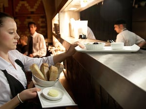 A waitress taking food from the pass to awaiting customers in a restaurant