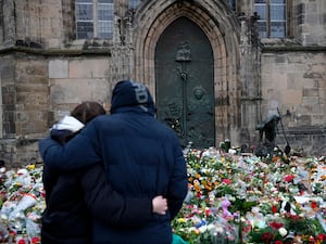 A couple embrace in front of a sea of flowers outside a church