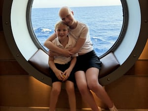 Liz Hatton sits in a ship window hugging her younger brother, Mateo