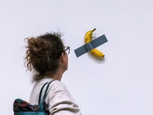 A woman looks at artist Maurizio Cattelan’s piece of art