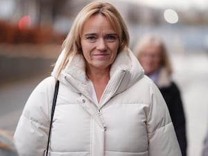 Sandie Peggie smiling while walking outside, wearing cream coat