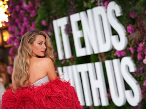 Blake Lively looking over her shoulder as she poses for photographers in front of a giant white letters spelling out It Ends With Us