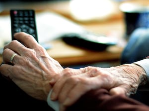 Old person's hands holding a TV remote control