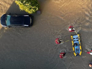 Drone image of a rescue boat with a man on board near a broken down car in floodwater