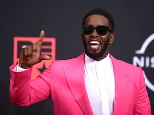 Sean 'Diddy' Combs in a pink jacket raises his finger