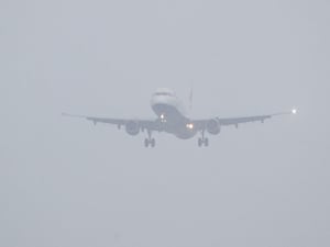 A plane comes into land in a thick fog sky