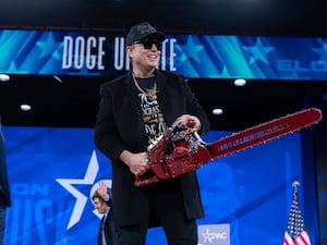 Elon Musk holds a chainsaw