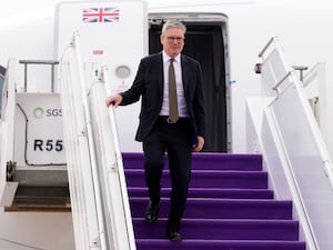 Sir Keir Starmer descends the steps from his plane after arriving in Riyadh, Saudi Arabia. The steps have a purple carpet.