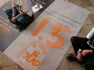 Charles Darwin's grave with '1.5 is dead' spray-painted on it in orange