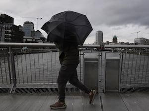 A person struggles with their umbrella