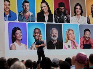 Meta chief Mark Zuckerberg on stage with backdrop of faces