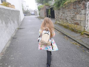 A girl walking down a lane with backpack