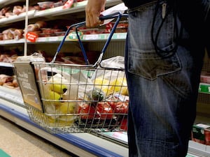 A person holding a basket of shopping in a supermarket