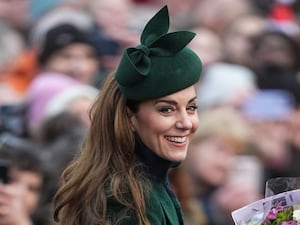 Kate smiles as she collects bouquets of flowers at Sandringham