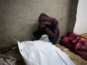 A man mourns over the bodies of two members of Abeid family who were killed in the Israeli bombardment in Maghazi, central Gaza Strip, at Al-Aqsa Martyrs Hospital in Deir al-Balah