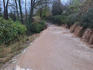 A wall collapsed at Bronygarth, near Oswestry, leaving water cascading down the road. Photo: PCSO David Hughes