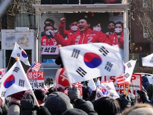 A TV screen shows an image of South Korean President Yoon Suk Yeol as supporters stage a rally to oppose his impeachment near the presidential residence in Seoul, South Korea