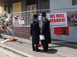 People gather outside the fire damaged Adass Israel Synagogue in Melbourne