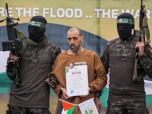 Israeli captive Eli Sharabi, who has been held hostage by Hamas in Gaza since October 7 2023, stands on a stage escorted by Hamas fighters before being handed over to the Red Cross in Deir al-Balah, central Gaza Strip