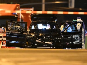 Forensic officers work on a damaged car