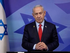 Benjamin Netanyahu standing beside an Israeli flag