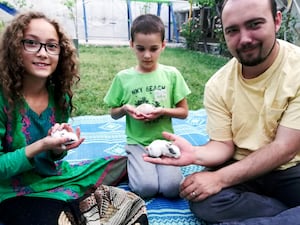 This family photo shows Ryan Corbett holding rabbits with his daughter Miriam and son Caleb in Kabul, Afghanistan in 2020