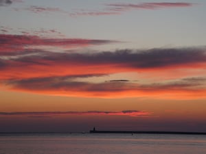 The sun begins to rise behind South Shields lighthouse on the North East coast