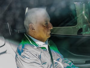 Retired Sydney broadcaster and former Australian national rugby coach Alan Jones in the back of an unmarked police car as he is transferred to Day St police station in Sydney