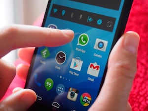 Finger poised above WhatsApp app on smartphone