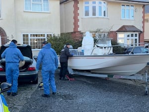 Forensic police officers search a boat and a car