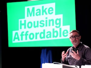 Eoin O Broin in front of a sign that says 'make housing affordable'