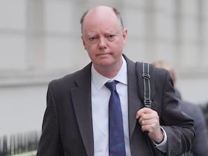 Professor Sir Chris Whitty walking while carrying a bag on his shoulder