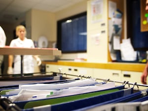 Patient notes with medical staff walking in the background