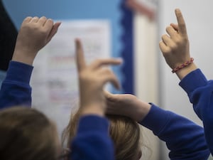 Children holding up their hands in class