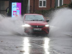 A vehicle is driven through floodwater after heavy rain in Warwick