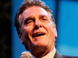 Chuck Woolery speaking into a microphone