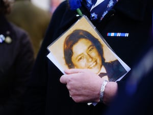 A close-up of a person's hand holding a picture of Yvonne Fletcher