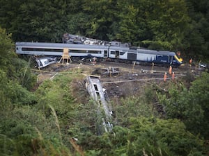 View of derailed train, with one carriage down an embankment