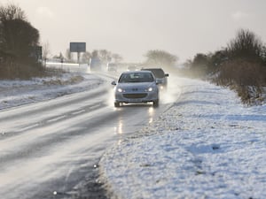 Cars driving on a road surrounded by snow