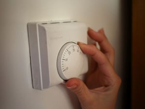 A person turning a thermostat on a wall