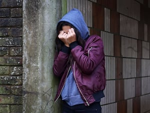 A distressed teenager covering their face with their hands