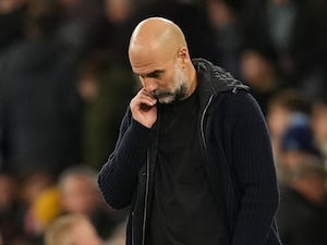 Pep Guardiola puts his hand to his mouth and looks down on the touchline